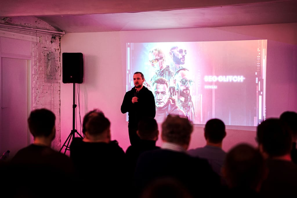 Robert Niechciał mówi obok slajdu SEO Glitch, publiczność w półmroku
