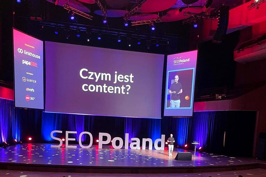 Robert Niechciał na scenie głównej SEO Poland Conference 2022 w ICE Kraków, na dużym ekranie slajd „Czym jest content?”