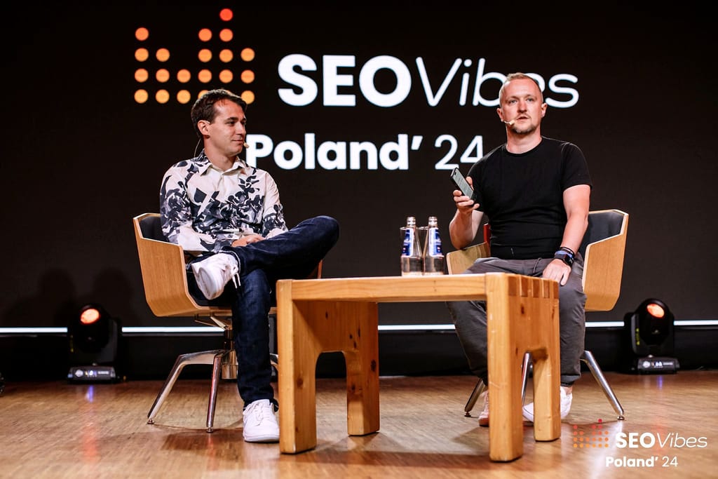 Robert Niechciał w rozmowie na scenie, w fotelach pod dużym logo SEO Vibes Poland '24
